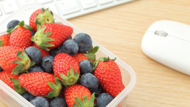 Image of a punnet of strawberries and blueberries next to a computer mouse and keyboard